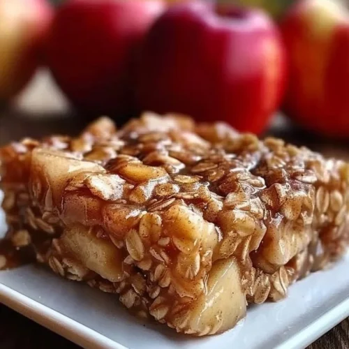 Slice of apple cinnamon baked oatmeal in a white bowl with apple slices
