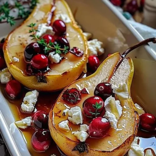 Baked pears topped with feta cheese, honey, and cranberries served on a plate.