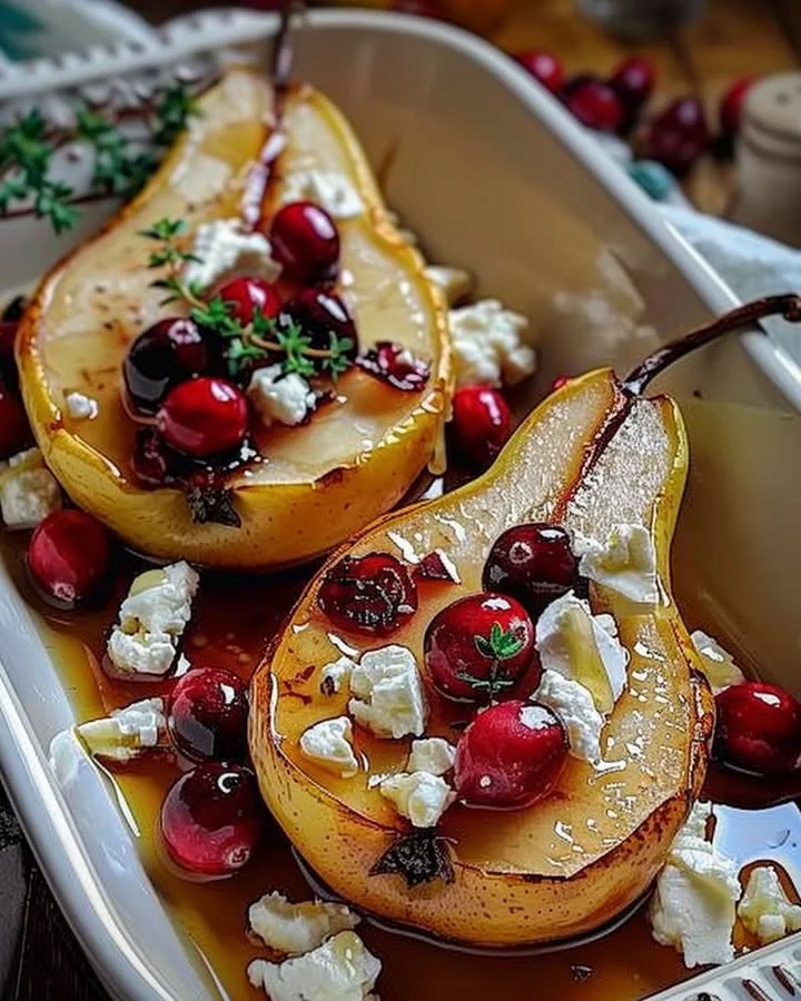 Baked pears topped with feta cheese, honey, and cranberries served on a plate.