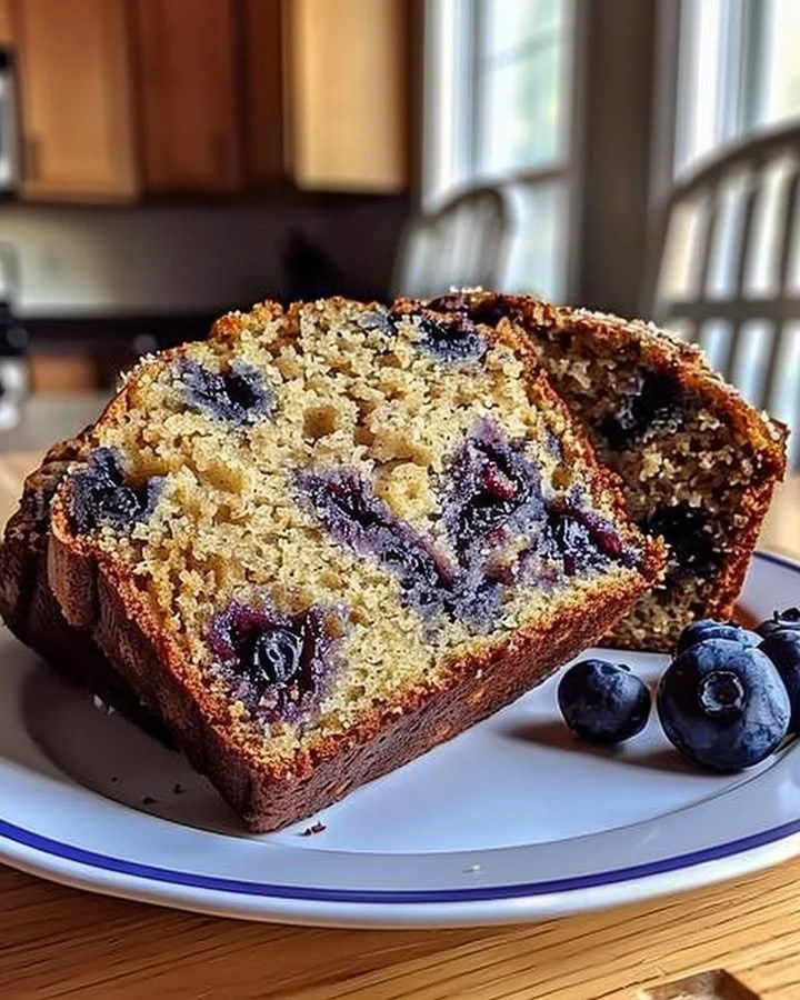 Loaf of freshly baked blueberry banana bread with blueberries and banana slices on top.
