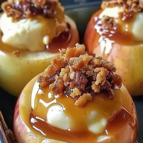 Baked cheesecake stuffed apples topped with caramel and nuts for a delicious dessert.