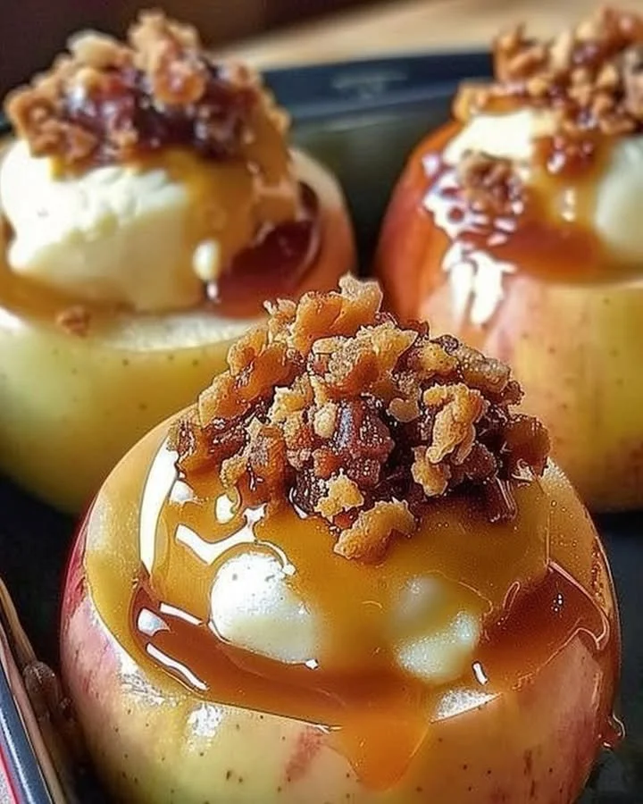Baked cheesecake stuffed apples topped with caramel and nuts for a delicious dessert.