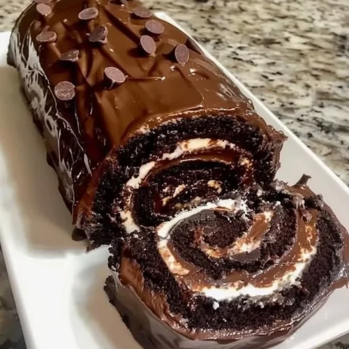 Delicious chocolate cake roll filled with creamy frosting and topped with chocolate shavings