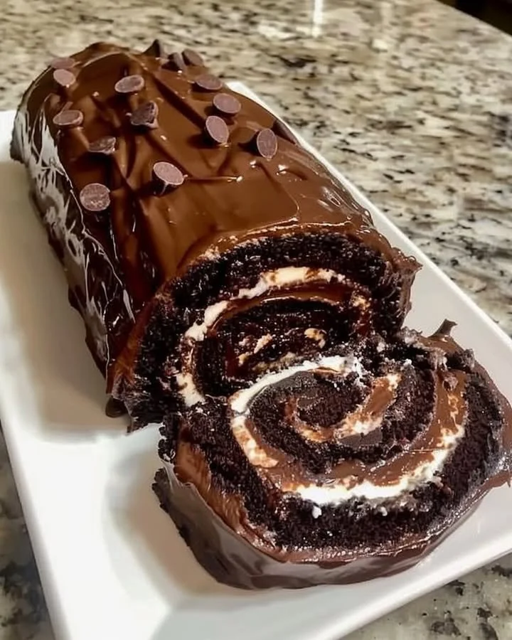 Delicious chocolate cake roll filled with creamy frosting and topped with chocolate shavings