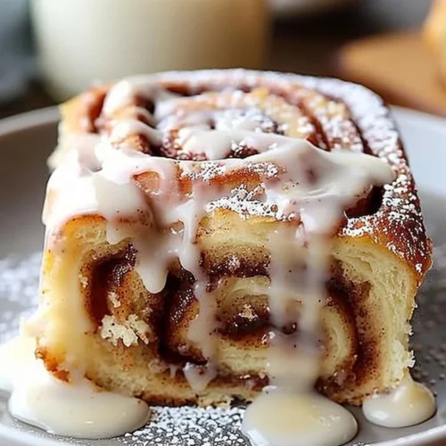 Delicious cinnamon roll poke cake topped with icing and cinnamon.