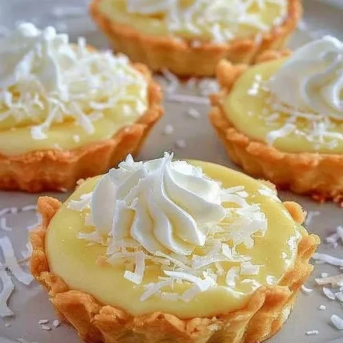 Delicious coconut cream tarts topped with whipped cream and coconut flakes.
