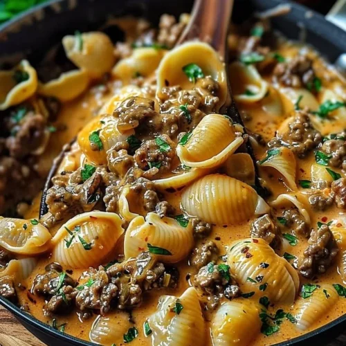 Creamy beef shells casserole dish topped with melted cheese and herbs