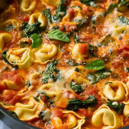 Creamy tomato basil tortellini skillet served in a white bowl with fresh herbs