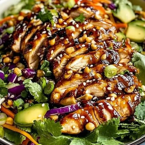 Bowl of crunchy Asian Sesame Chicken Salad with colorful vegetables and sesame dressing.