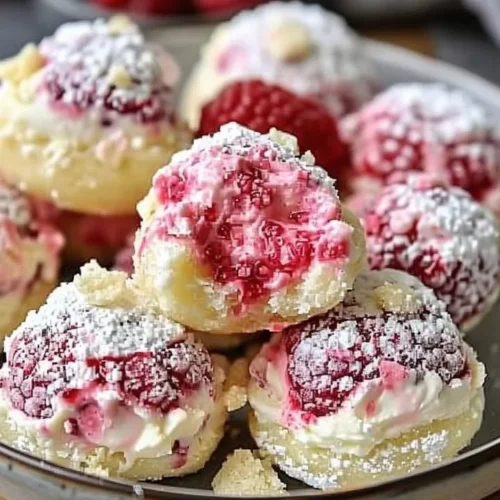 Homemade raspberry cream cheese bites on a plate, garnished with fresh raspberries.