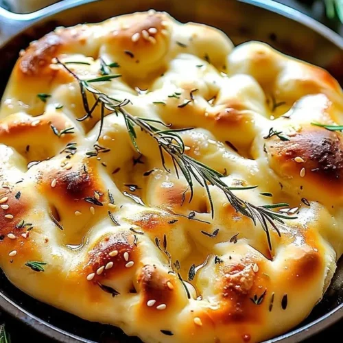 Delicious homemade focaccia bread fresh out of the oven, topped with herbs.