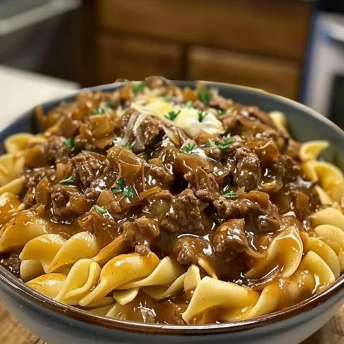 Delicious bowl of French onion beef and noodles topped with melted cheese