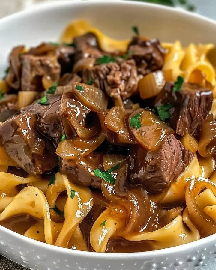 Delicious French onion beef and noodles served in a bowl with melted cheese