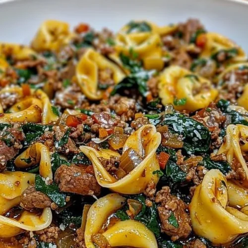 Plate of Garlic Butter Beef and Spinach Tortellini garnished with herbs