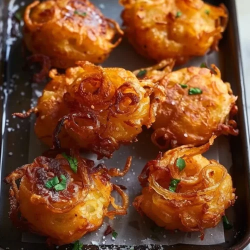 Crispy golden onion fritters served on a plate with dipping sauce