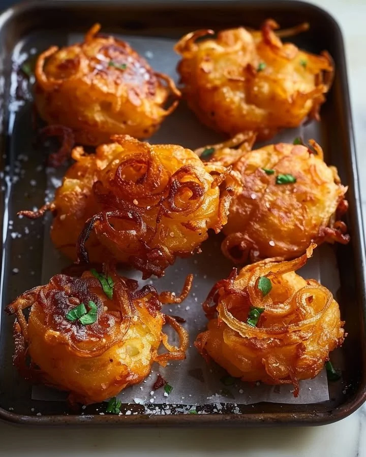Crispy golden onion fritters served on a plate with dipping sauce