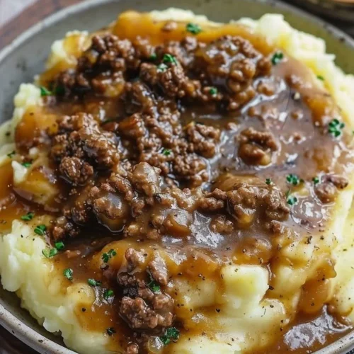 Ground beef and gravy served over creamy mashed potatoes in a warm bowl.
