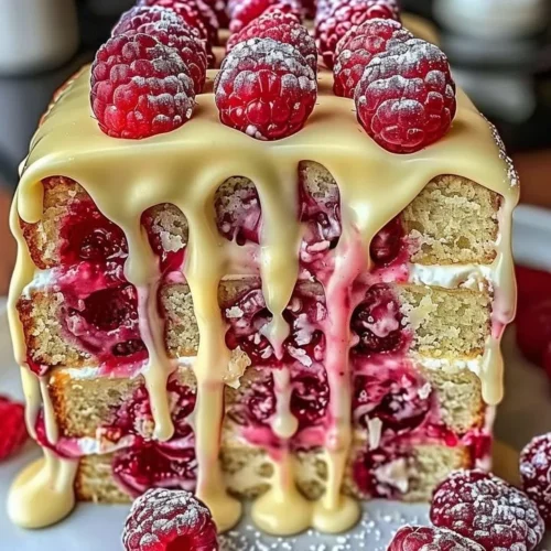 Heavenly White Chocolate Raspberry Cake topped with fresh raspberries and whipped cream.