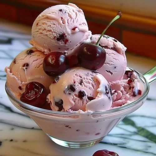 A delicious bowl of homemade cherry ice cream with fresh cherries on top.