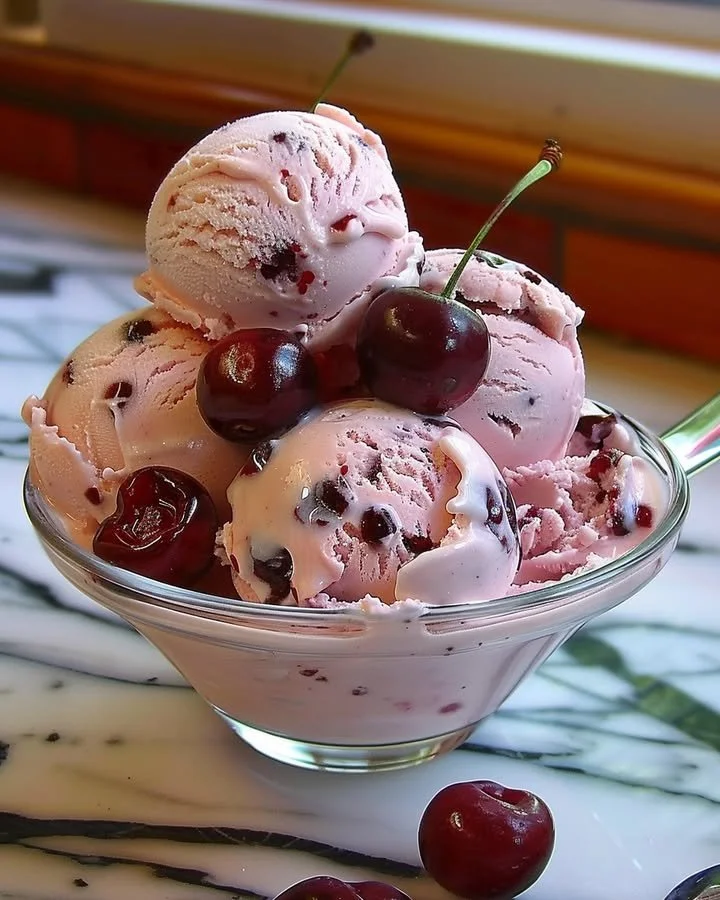 A delicious bowl of homemade cherry ice cream with fresh cherries on top.