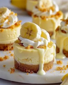 Mini banana pudding cheesecakes topped with whipped cream and banana slices