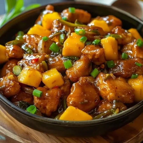 Plate of Mango Chili Chicken garnished with fresh herbs