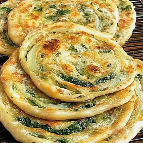 Pan-fried green onion and spinach flatbread served on a wooden board