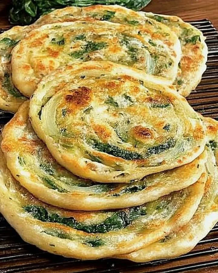 Pan-fried green onion and spinach flatbread served on a wooden board