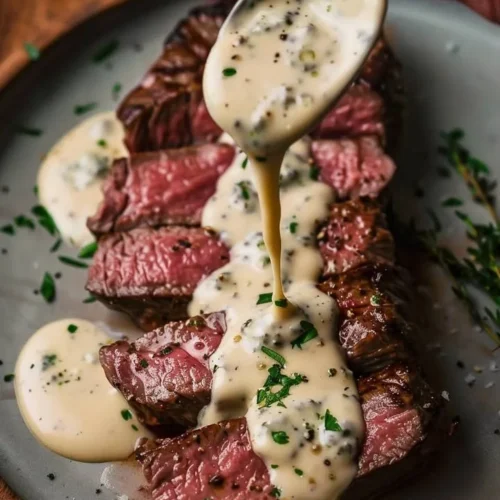 Pan-seared New York Strip Steak with Gorgonzola cream sauce on a white plate