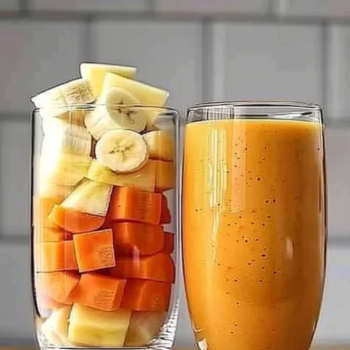 A vibrant Pineapple Orange Carrot Smoothie in a glass with fresh ingredients.