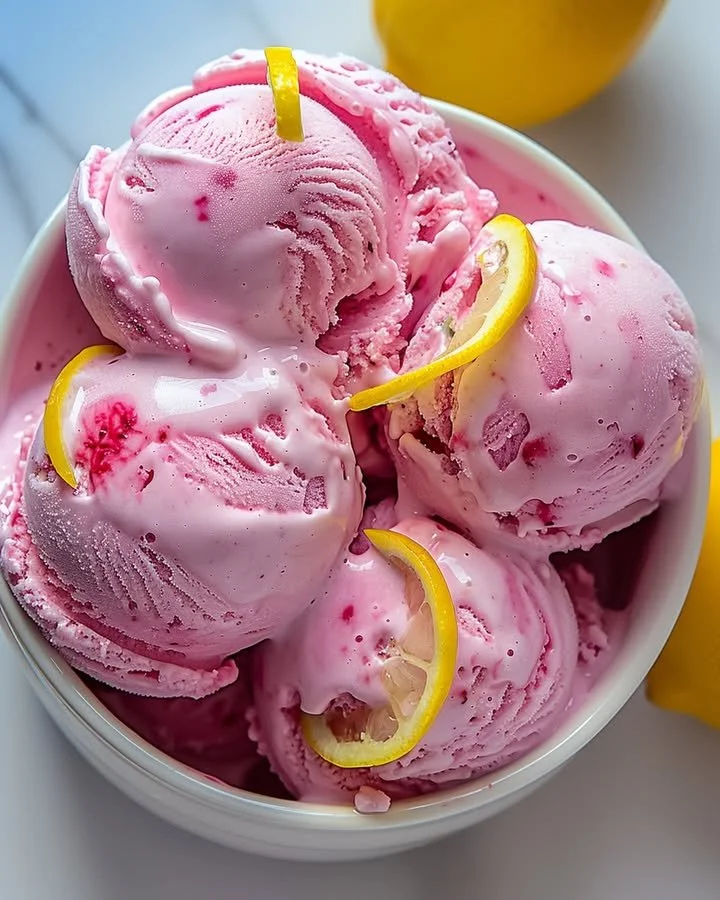 Delicious pink lemonade ice cream in a bowl with a slice of lemon on top.