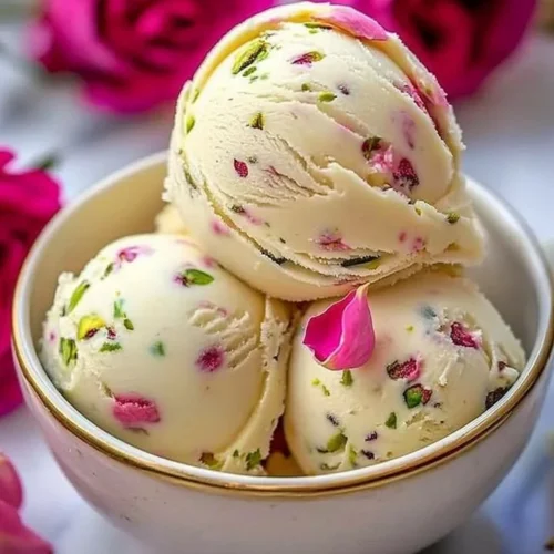Creamy pistachio cheesecake ice cream in a bowl with a sprinkle of pistachios on top.