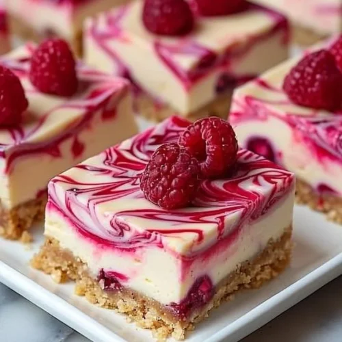 Delicious raspberry swirl cheesecake bars on a white plate.