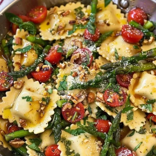 Ravioli with tomatoes, asparagus, garlic, and herbs served in a bowl