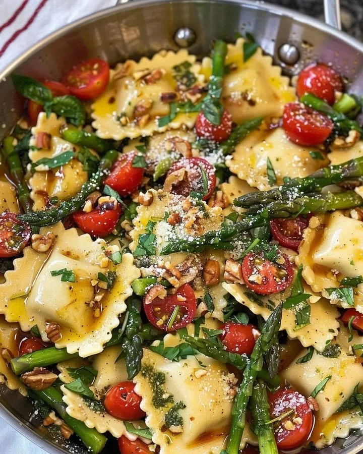 Ravioli with tomatoes, asparagus, garlic, and herbs served in a bowl