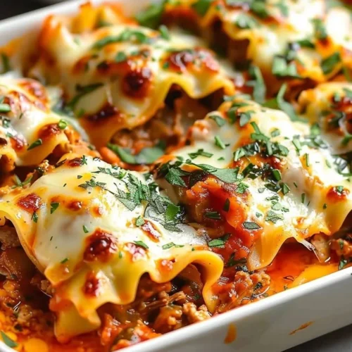 Delicious Short Rib Lasagna Rolls served on a plate with fresh herbs.