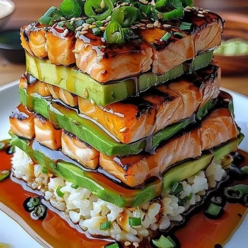 Teriyaki salmon avocado rice stack served on a plate with fresh ingredients