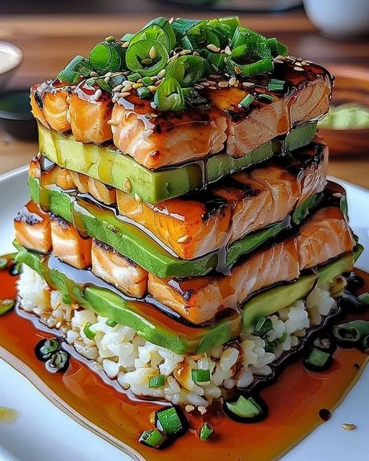 Teriyaki salmon avocado rice stack served on a plate with fresh ingredients